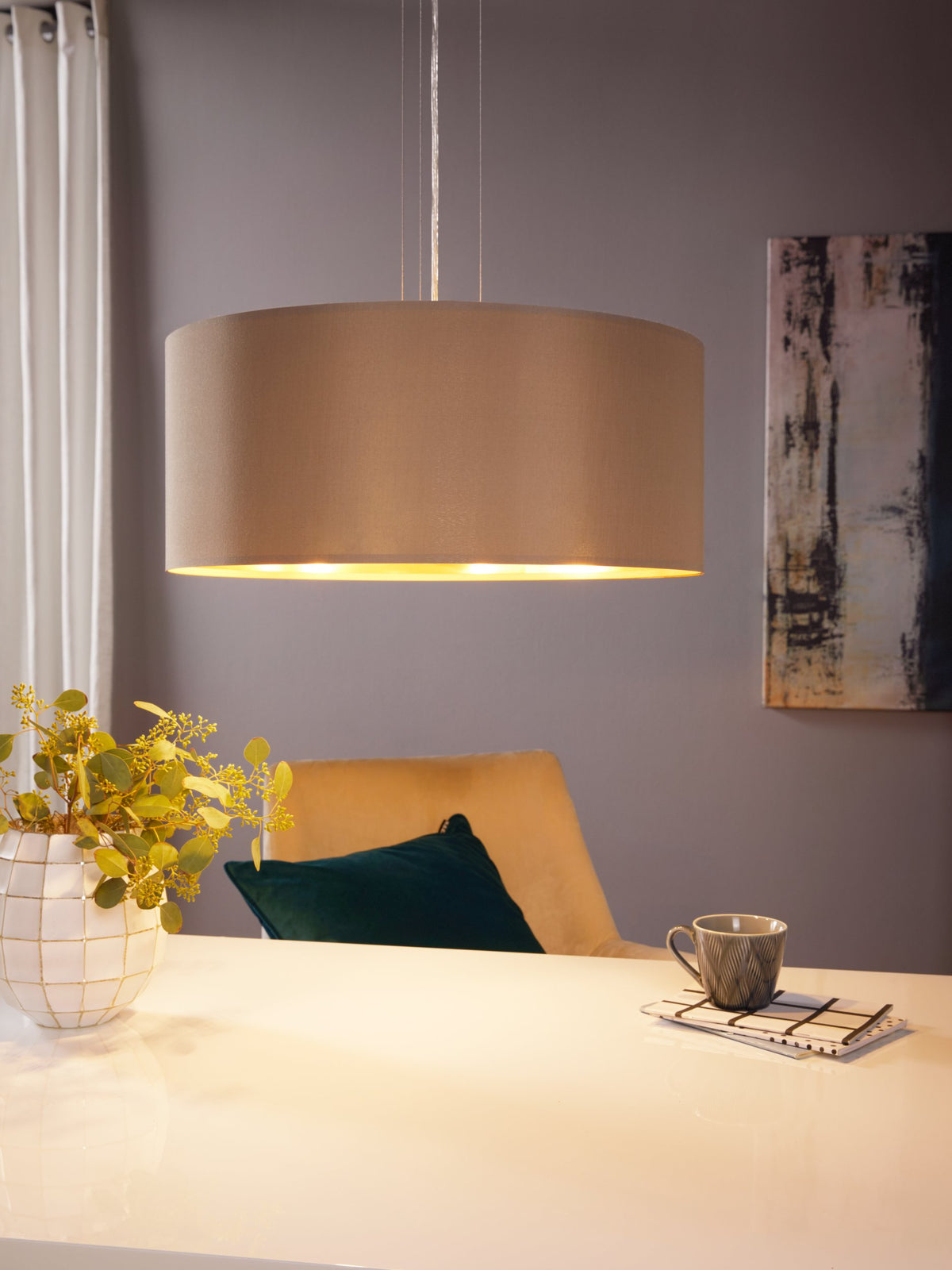 Mise en ambiance au-dessus d'une table avec plante, tasse et fauteuil, lumière chaude.