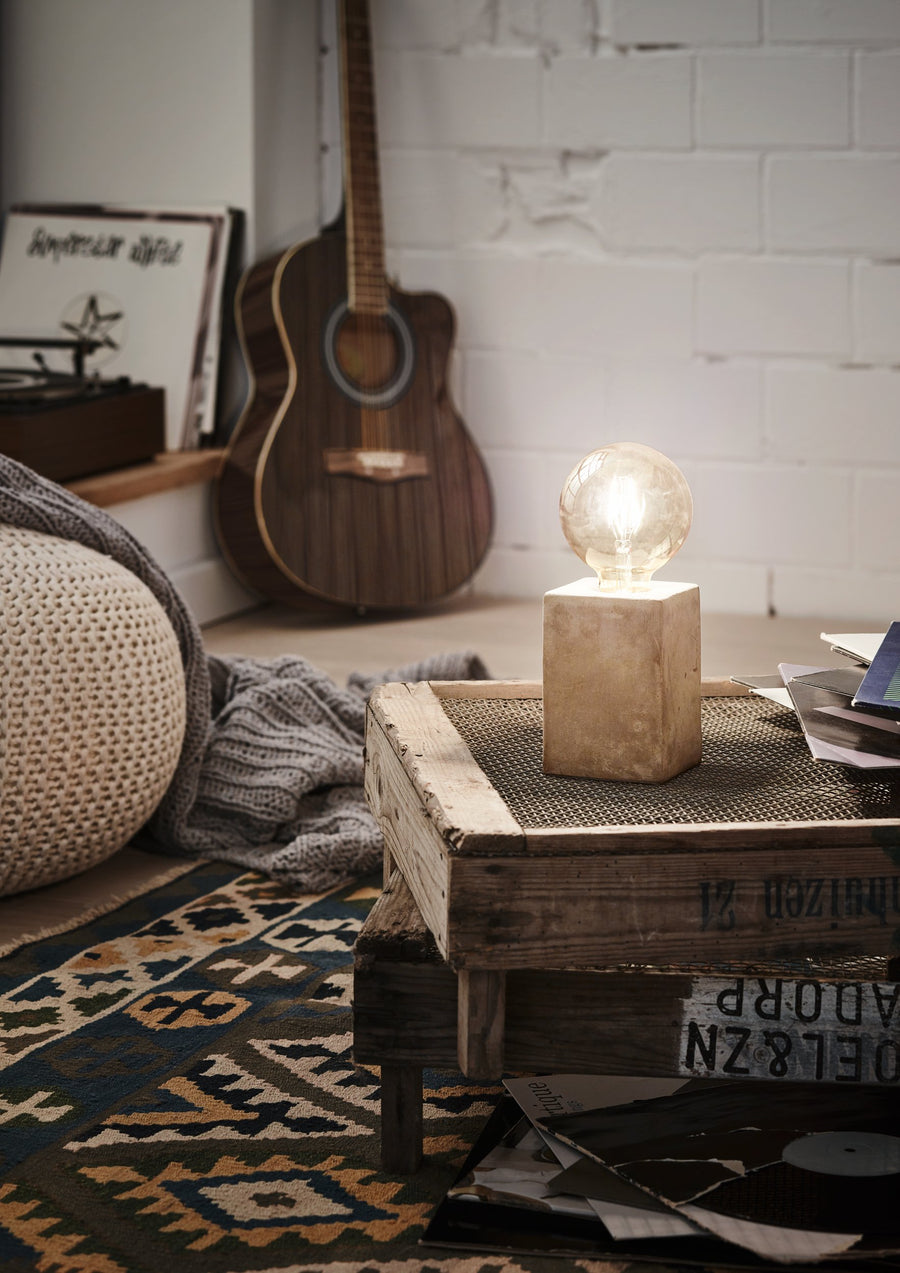 Lampe allumée posée sur une caisse en bois dans un salon avec guitare