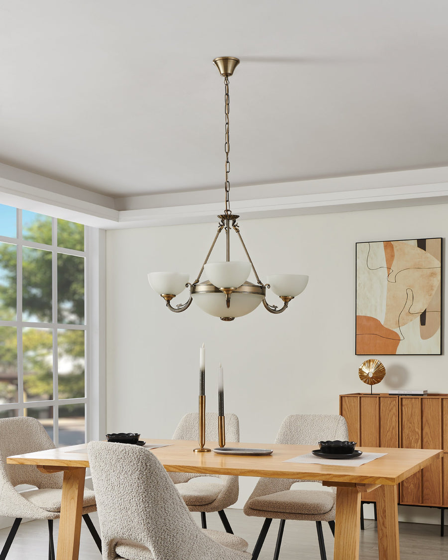 Vue en situation du même luminaire éteint, au-dessus d'une table avec chaises et décor mural.