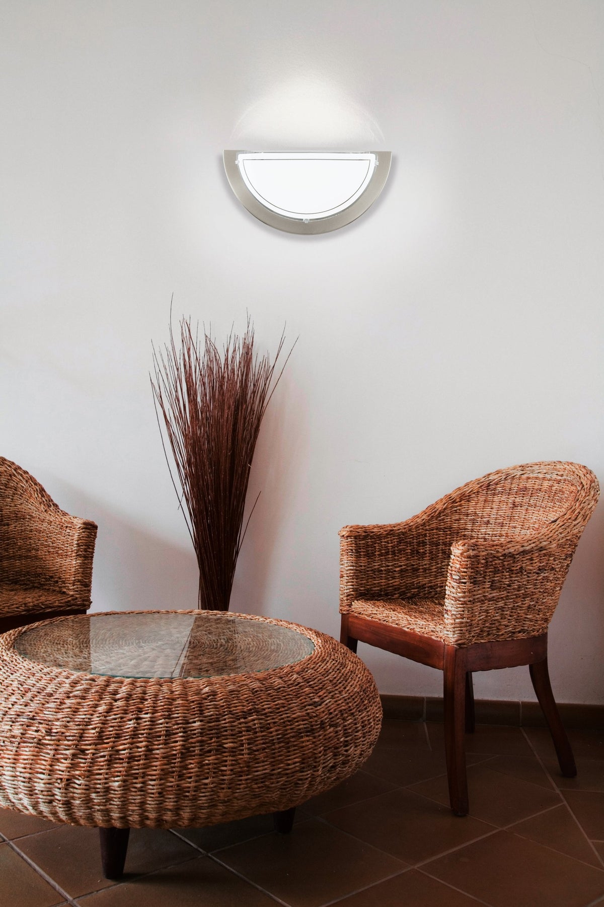 Mise en ambiance salon avec fauteuils rotin et applique murale allumée
