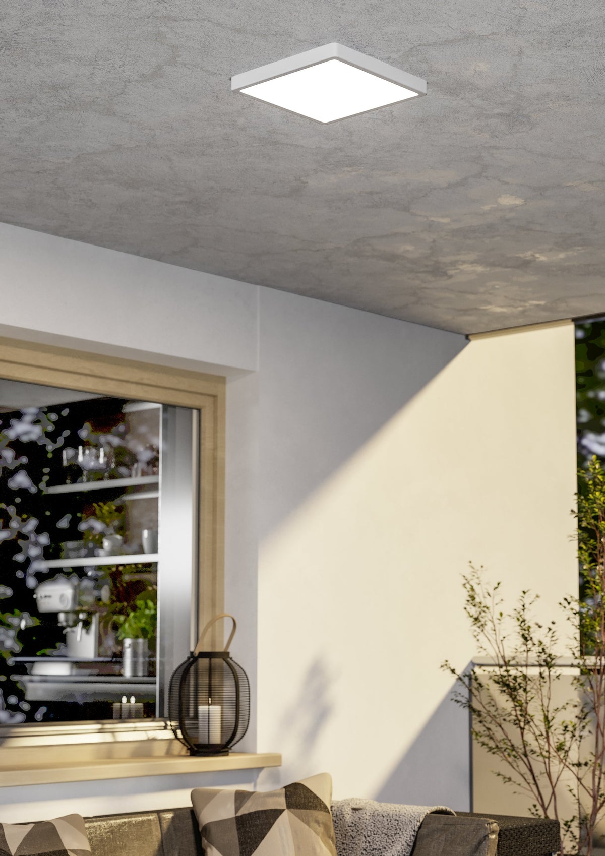 Luminaire carré blanc fixé au plafond d'une terrasse couverte, éclairant un mur extérieur.