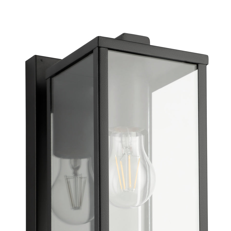 Détail rapproché de l'angle du cadre noir et de l'ampoule à filament vue dans le verre