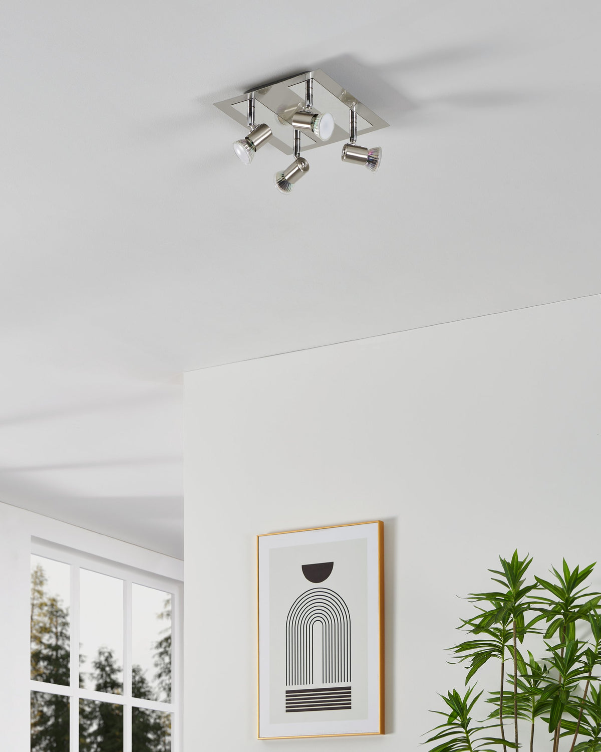 Ambiance au plafond du spot quatre têtes, lumière allumée dans un intérieur épuré avec cadre graphique.