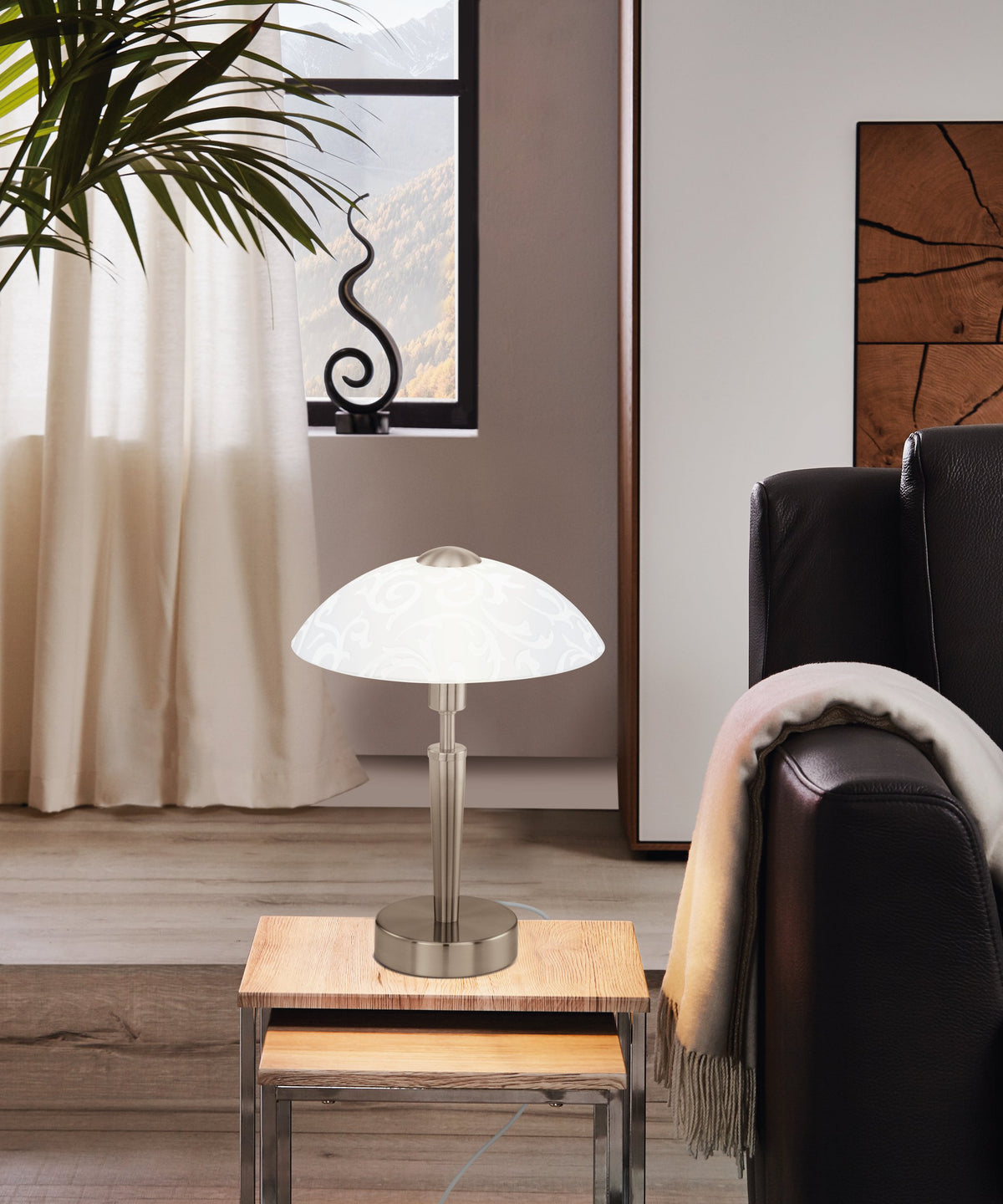 Mise en ambiance: lampe posée sur table basse en bois clair, près d'un canapé en cuir.