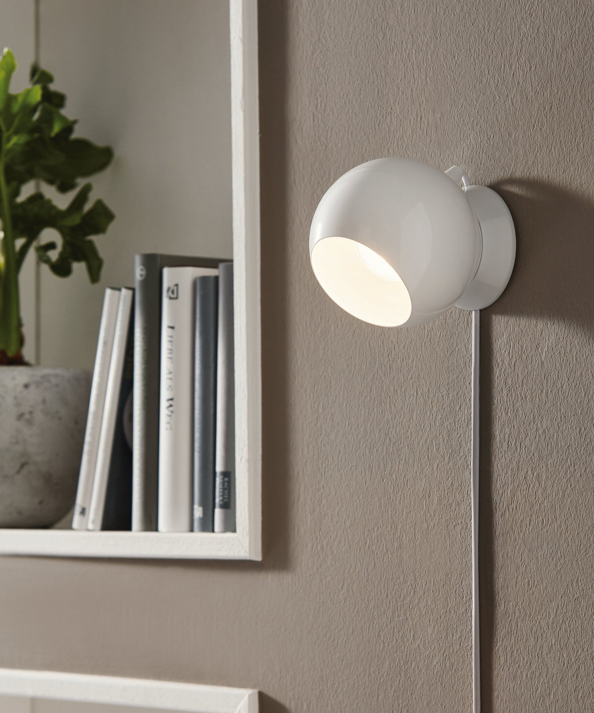 Mise en ambiance murale, lampe blanche allumée près d'une étagère et d'une plante
