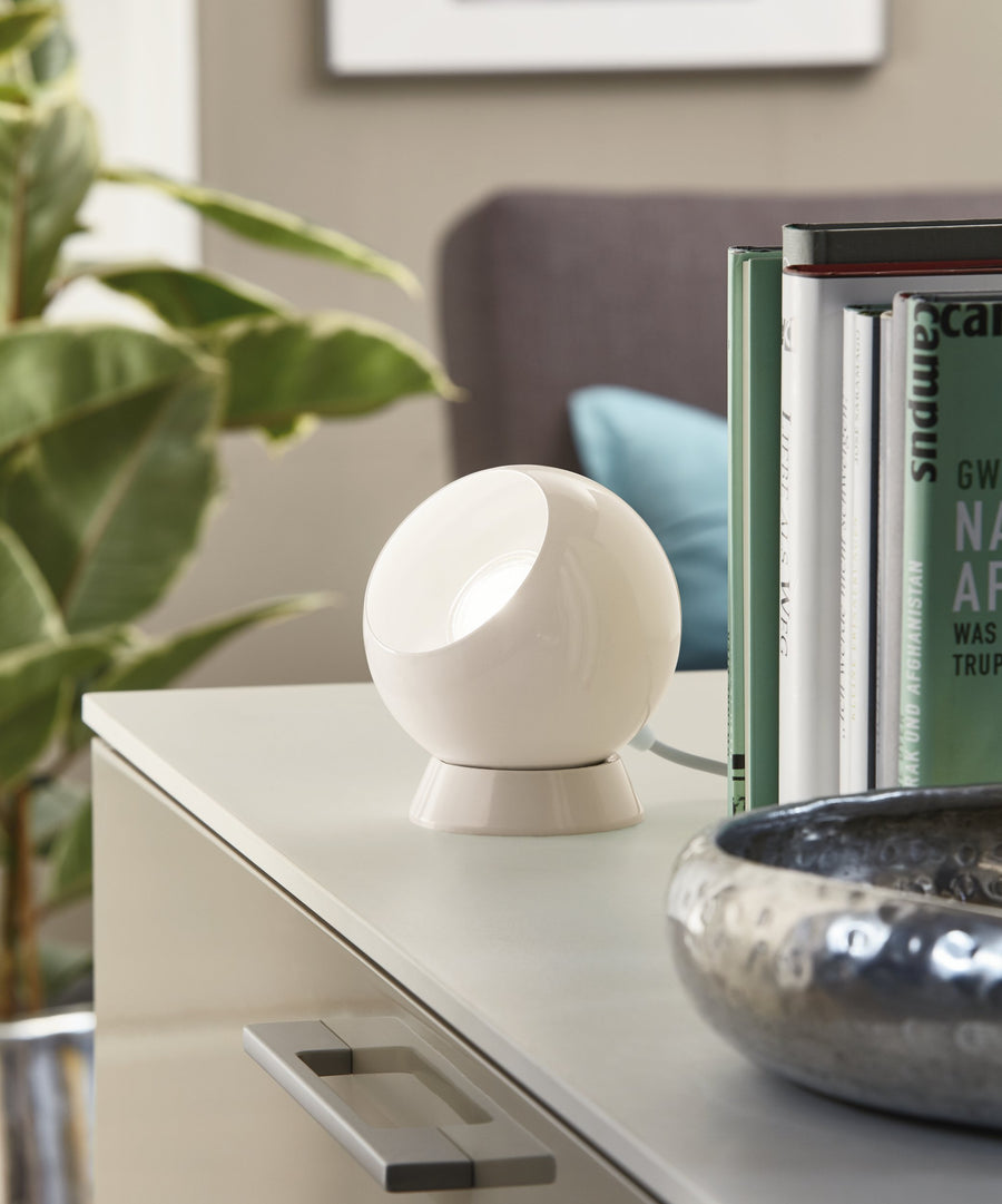 Lampe posée sur une commode blanche dans une chambre, plantes et livres