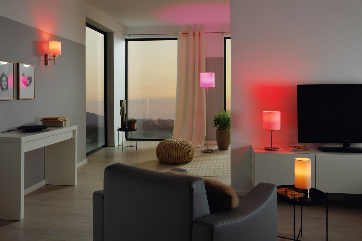 Mise en ambiance du salon, applique allumée diffusant une lumière rose sur le mur