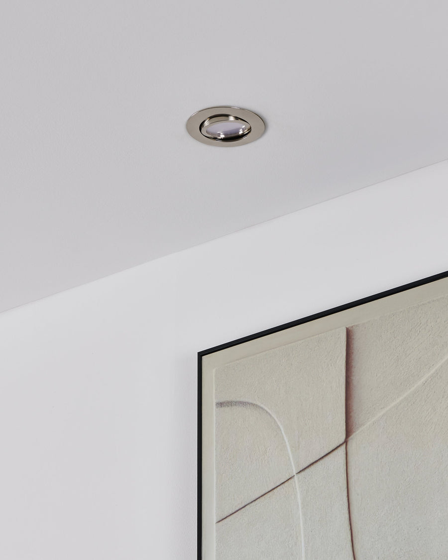 Vue de plafond avec spot éteint, anneau chromé brillant et cadre textile clair
