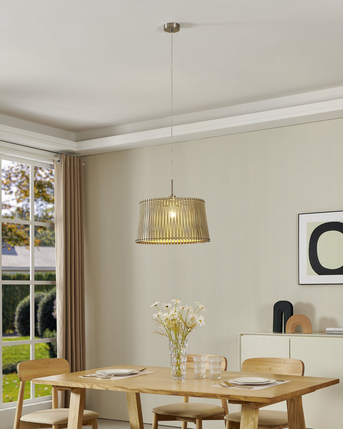 Suspension allumée au-dessus d'une table à manger en bois clair dans une pièce lumineuse.