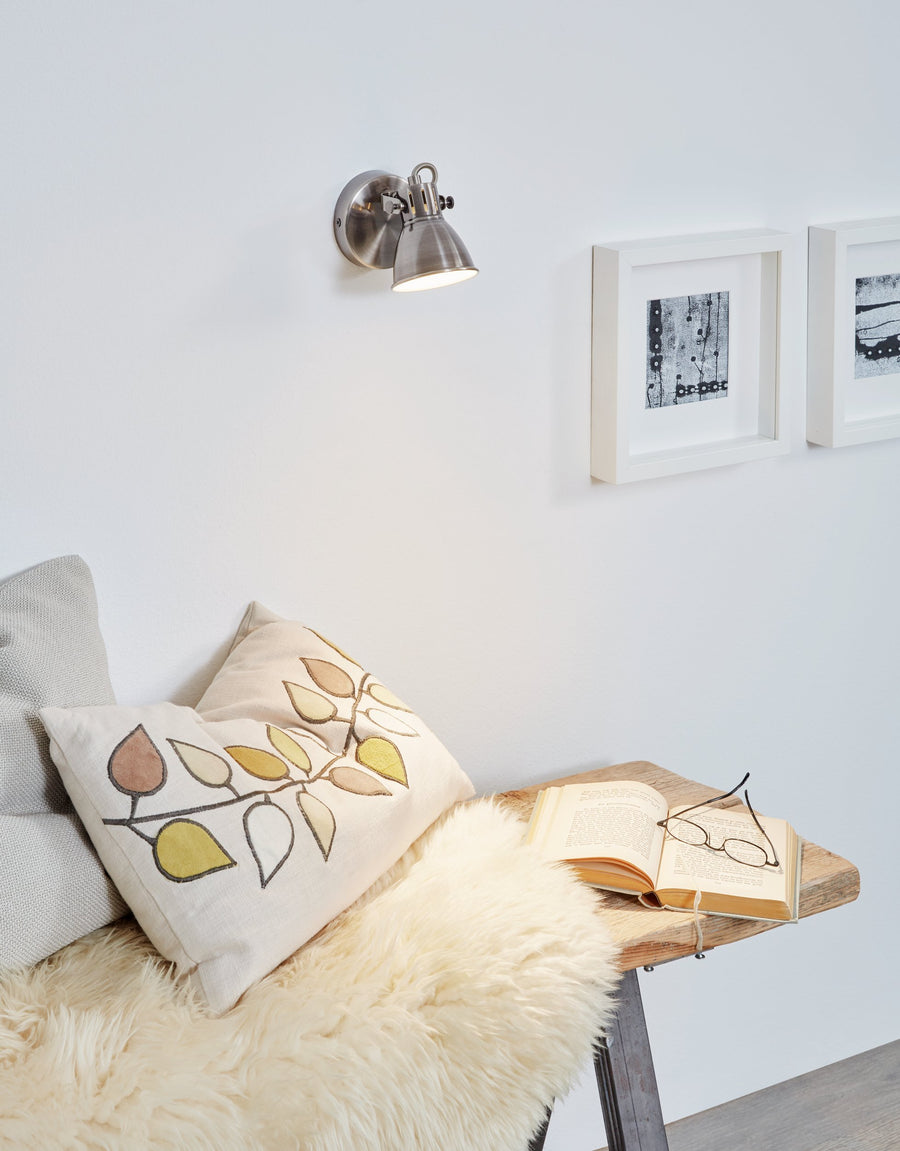 Mise en ambiance, spot fixé au mur au-dessus d'un canapé à coussins brodés