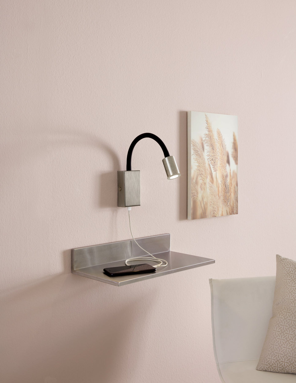 Mise en ambiance chambre rose : applique allumée au-dessus d'une étagère métallique avec téléphone en charge