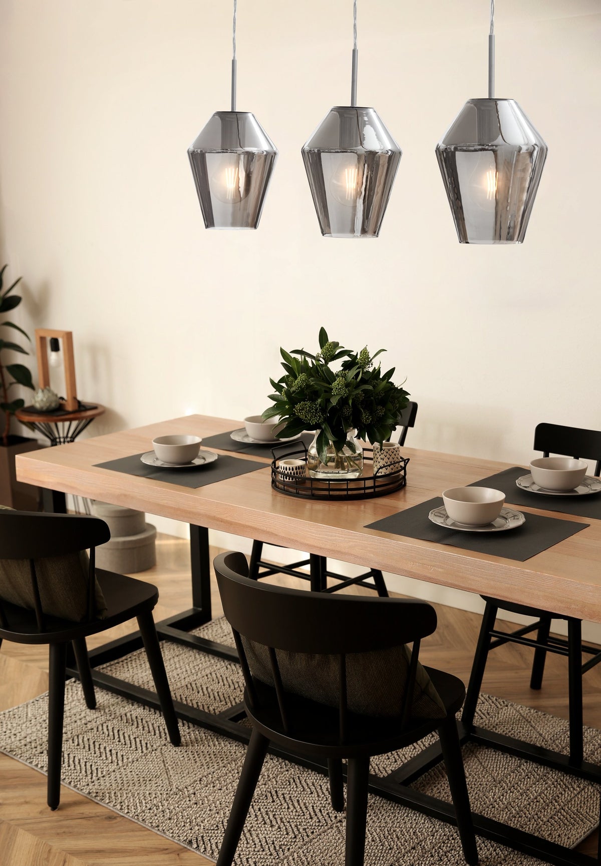 Ambiance salle à manger bois clair, suspensions allumées au-dessus de la table dressée