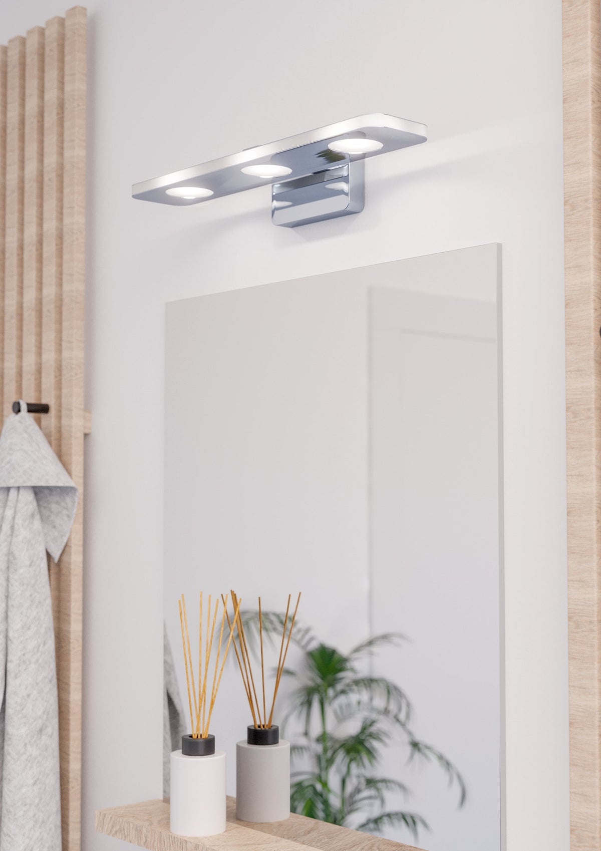Mise en ambiance salle de bain, applique allumée au-dessus d'un miroir et d'un meuble