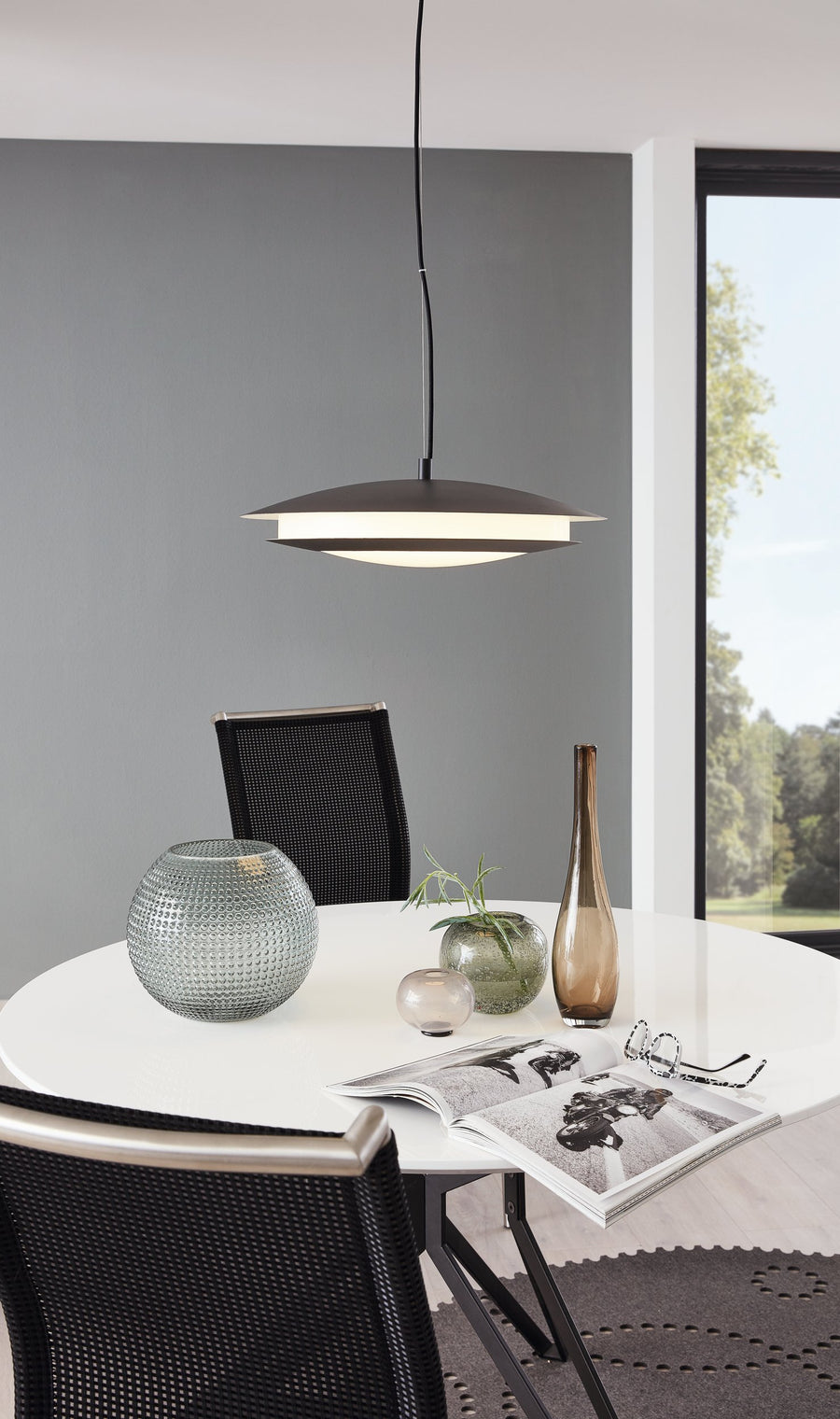 Luminaire suspendu allumé au-dessus d'une table ronde blanche avec vases décoratifs