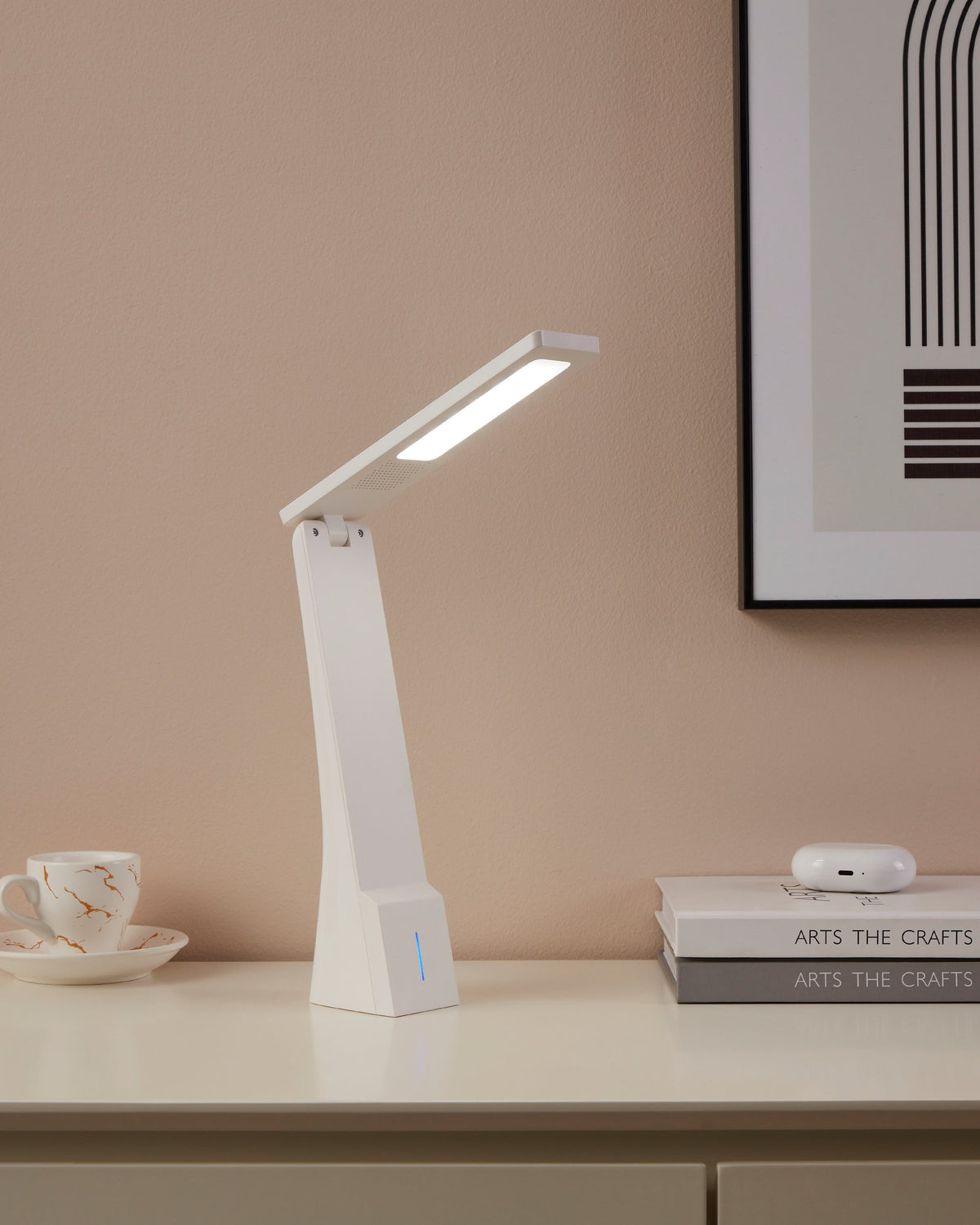 Lampe allumée posée sur un meuble, tasse marbrée et livres en arrière-plan