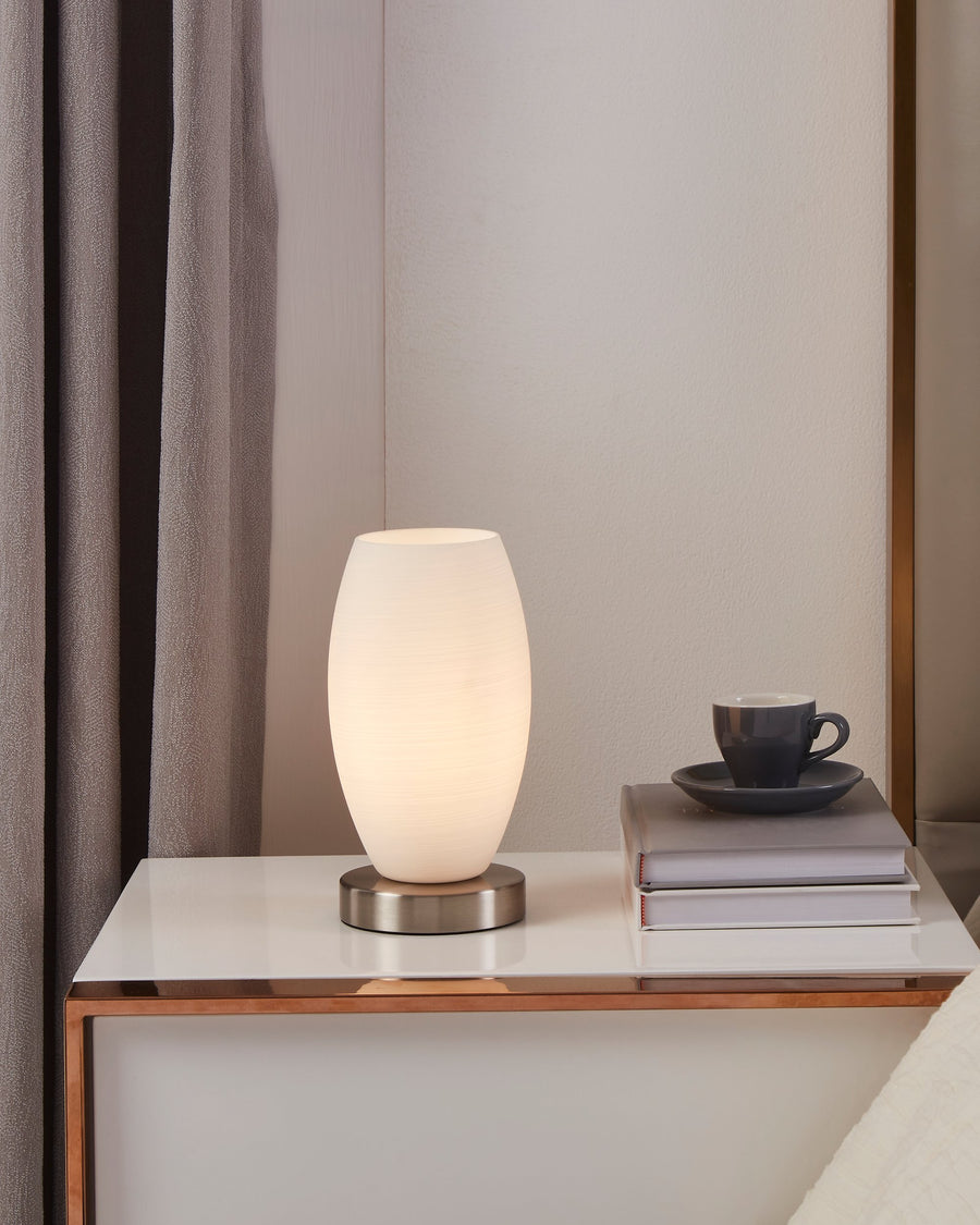 Ambiance chaleureuse de chevet avec lampe allumée, livres et tasse foncée