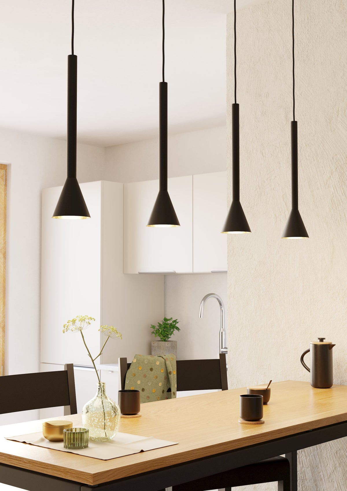 Mise en ambiance au-dessus d'une table de cuisine, quatre suspensions noires allumées.