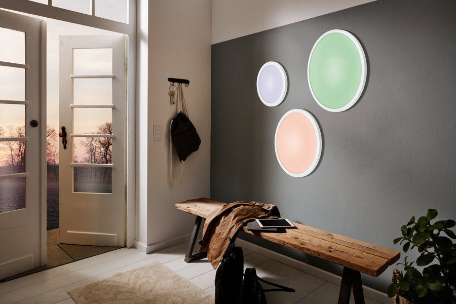 Entrée avec trois plafonniers ronds colorés fixés au mur près d'un banc
