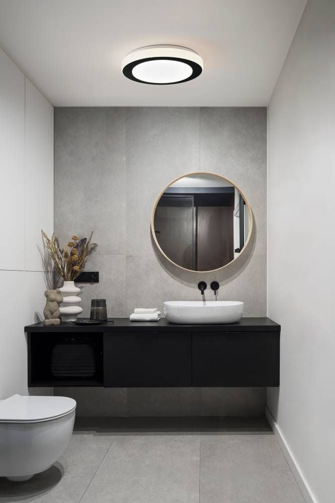 Plafonnier rond allumé au plafond d'une salle de bain moderne et grise
