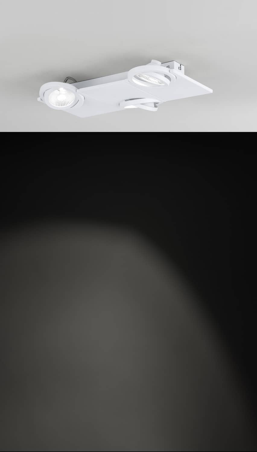 Luminaire blanc installé au plafond et faisceau lumineux projeté sur une surface sombre.