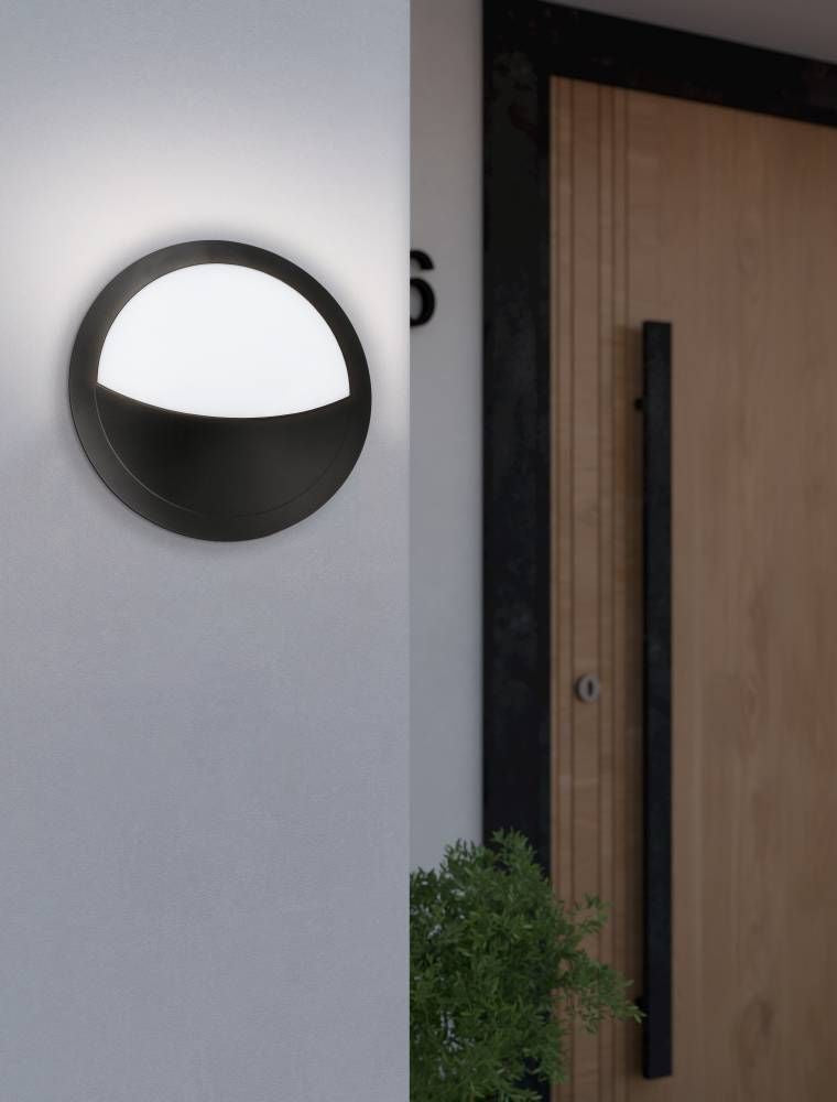 Applique extérieure allumée fixée sur un mur blanc près d'une porte en bois