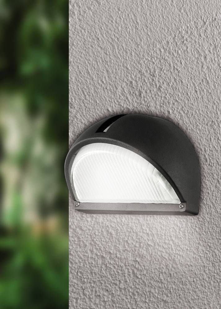 Applique fixée sur un mur gris texturé, fond de jardin verdoyant flou