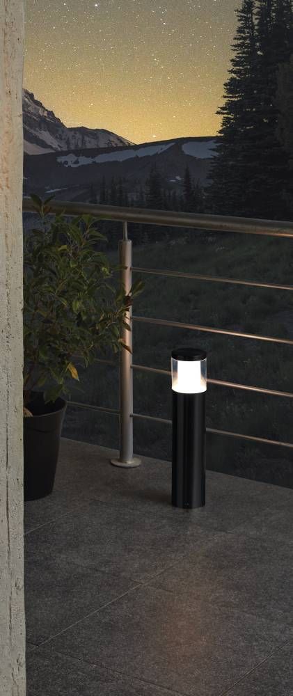 Lampadaire noir allumé sur terrasse la nuit avec montagnes en arrière-plan