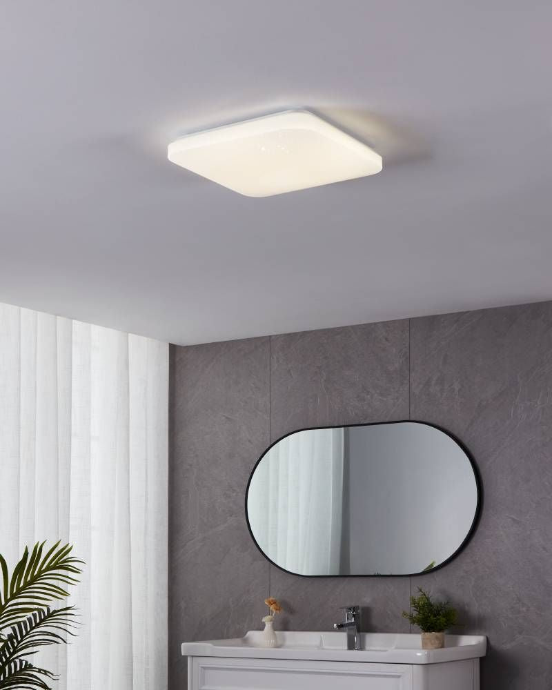 Luminaire allumé fixé au plafond d'une salle de bain grise avec vasque et miroir