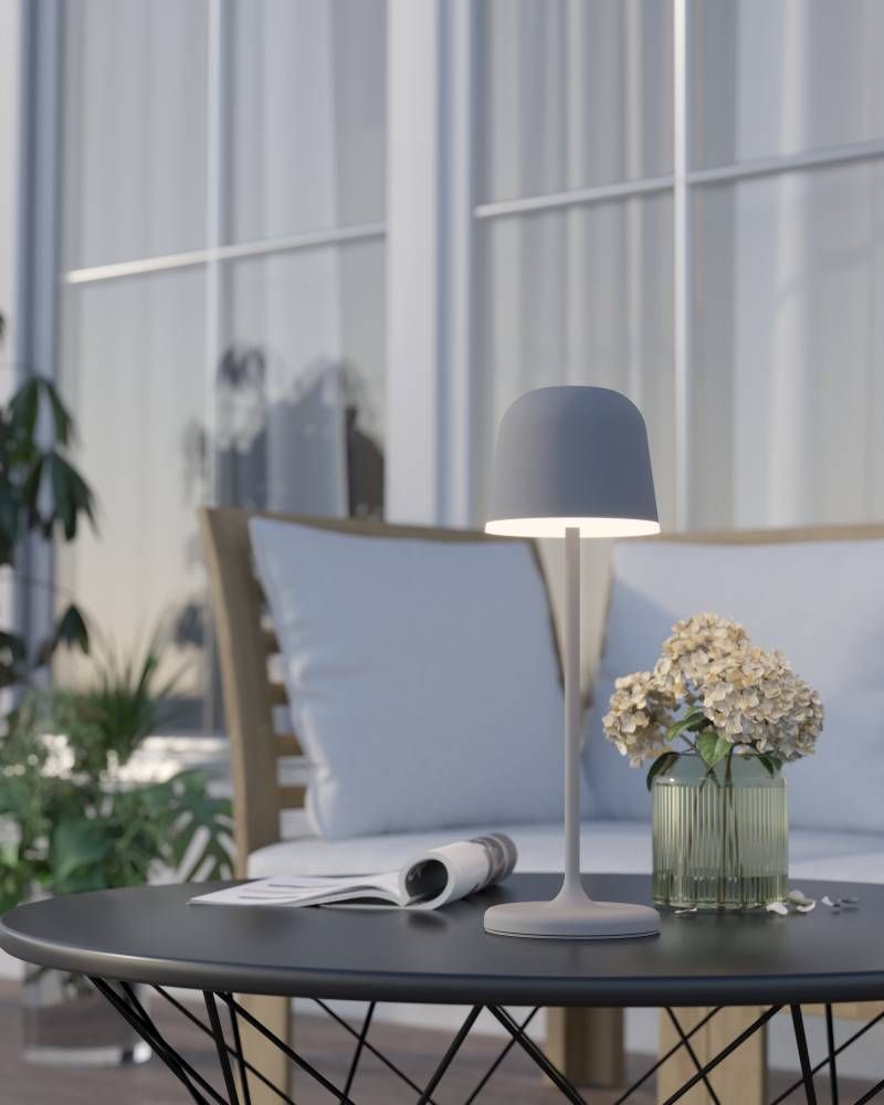 Mise en ambiance de la lampe posée sur table basse, terrasse avec coussins