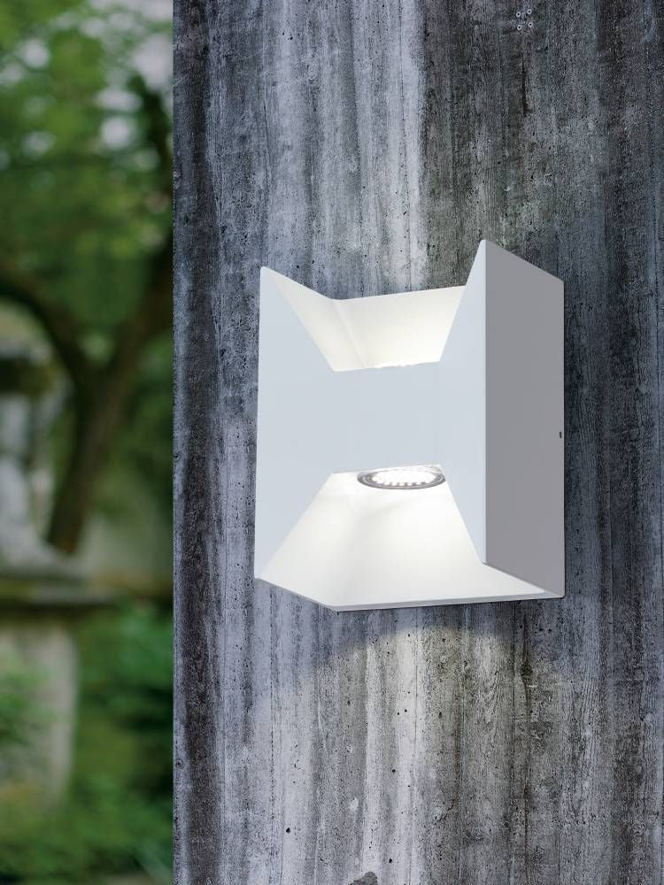 Applique blanche allumée fixée sur un mur extérieur en béton gris texturé.
