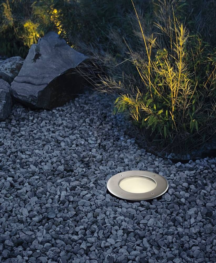 Luminaire encastré dans un lit de gravier, éclairant des bambous dans un jardin la nuit