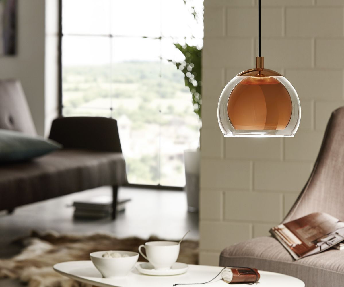 Mise en ambiance salon clair, suspension cuivrée au-dessus d'une table basse