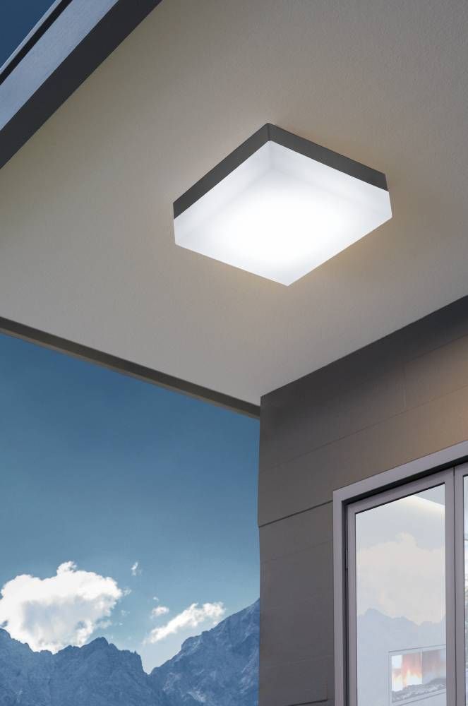 Luminaire allumé fixé au plafond d'une terrasse, montagnes et ciel bleu en fond