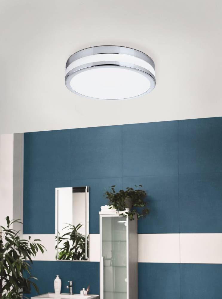 Luminaire installé au plafond d'une salle de bain bleue avec miroir et plante