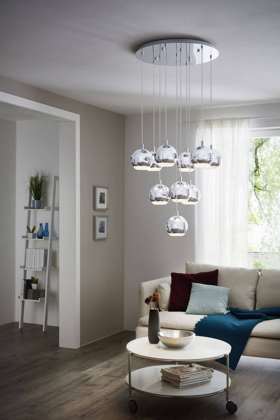 Suspension chromée installée au-dessus d'une table basse dans un salon moderne