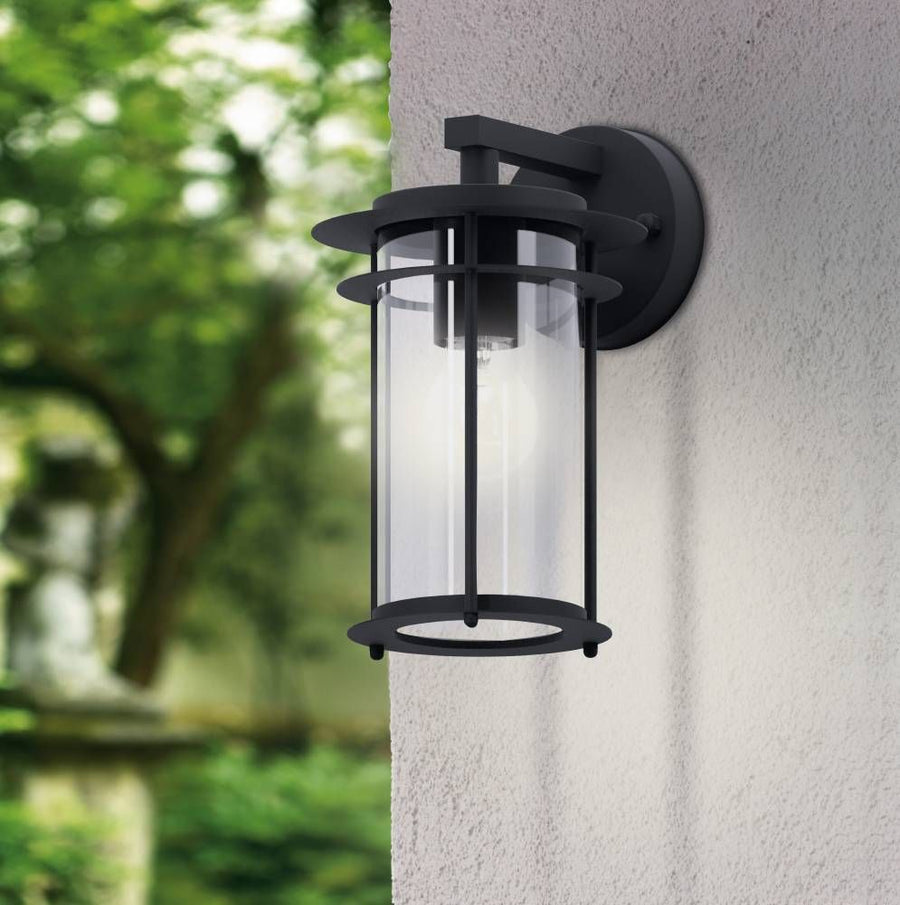Luminaire allumé fixé sur mur gris, arrière-plan de feuillage vert flou