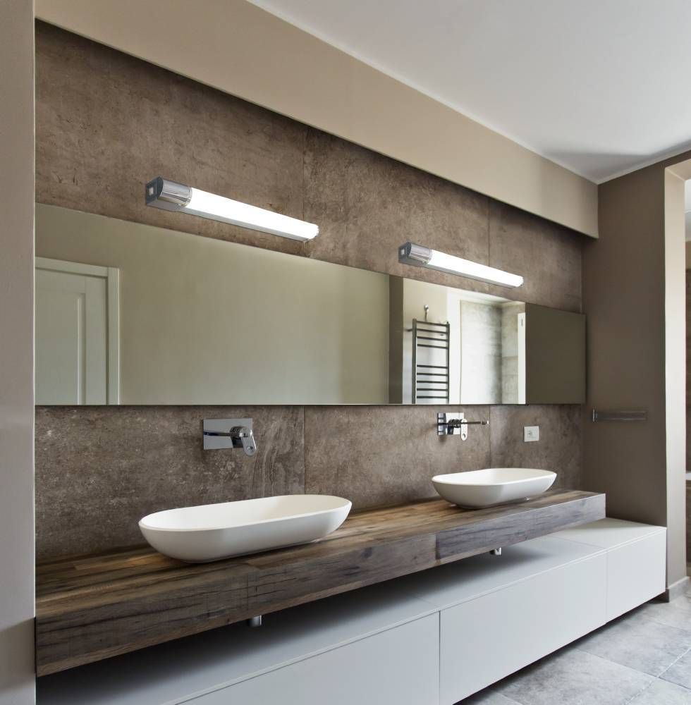 Deux luminaires identiques fixés au mur au-dessus de vasques dans une salle de bain moderne.