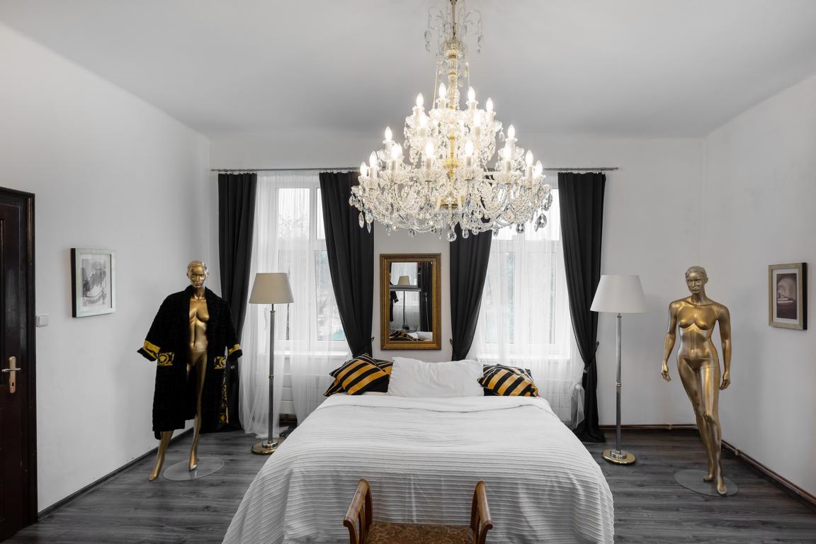 Mise en ambiance dans une chambre blanche avec mannequins dorés et rideaux noirs