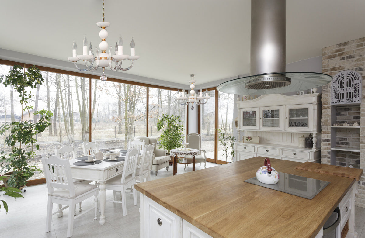 Mise en ambiance dans une cuisine lumineuse, deux lustres suspendus devant de grandes baies vitrées