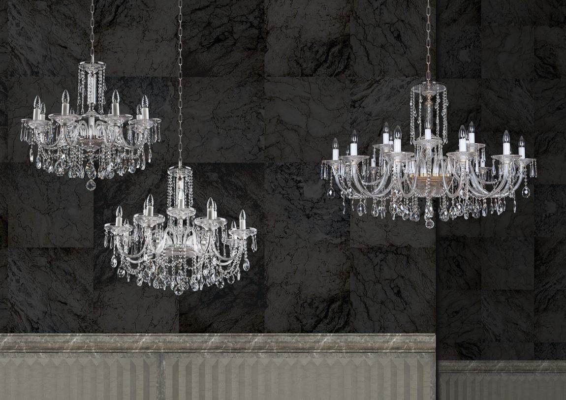 Trois lustres en cristal de tailles différentes devant un mur en marbre noir.