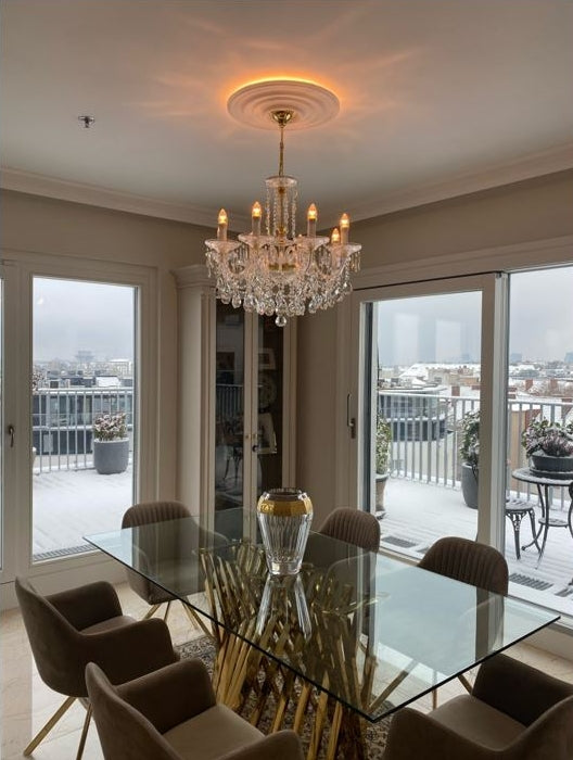 Lustre en cristal suspendu dans une salle à manger près de baies vitrées.
