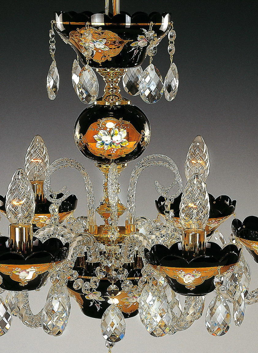 Gros plan du lustre montrant bol noir et fleurs dorées, bras et cristaux taillés.
