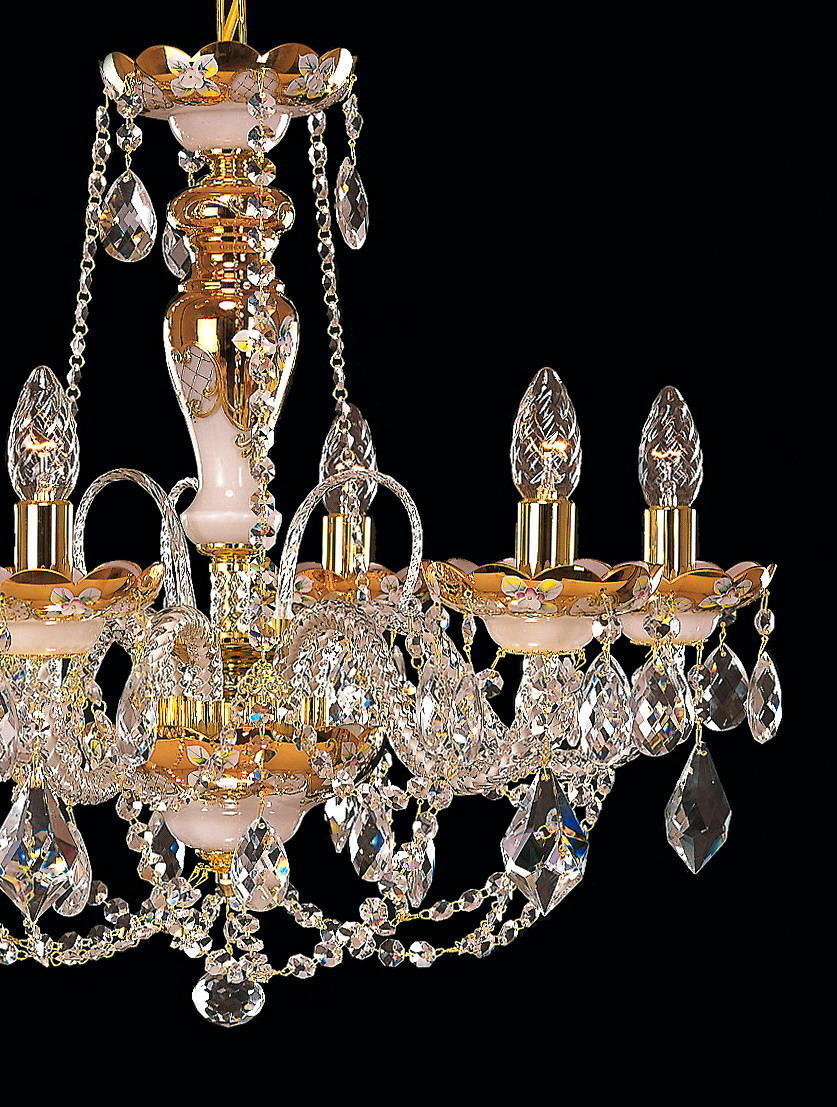 Détail du lustre : bras courbés dorés, chaînes de cristal et gouttes taillées