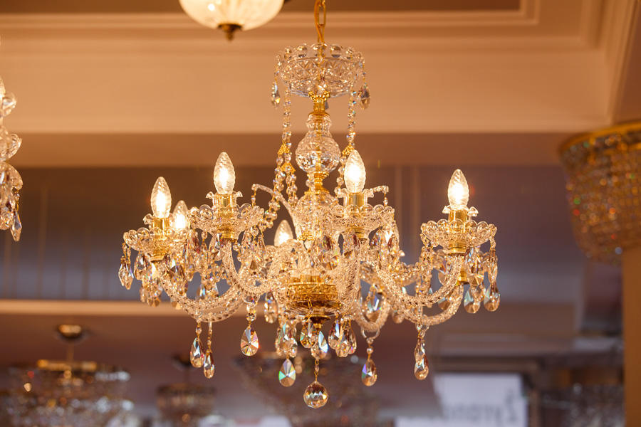 Lustre en cristal allumé dans un showroom, ambiance chaude et dorée