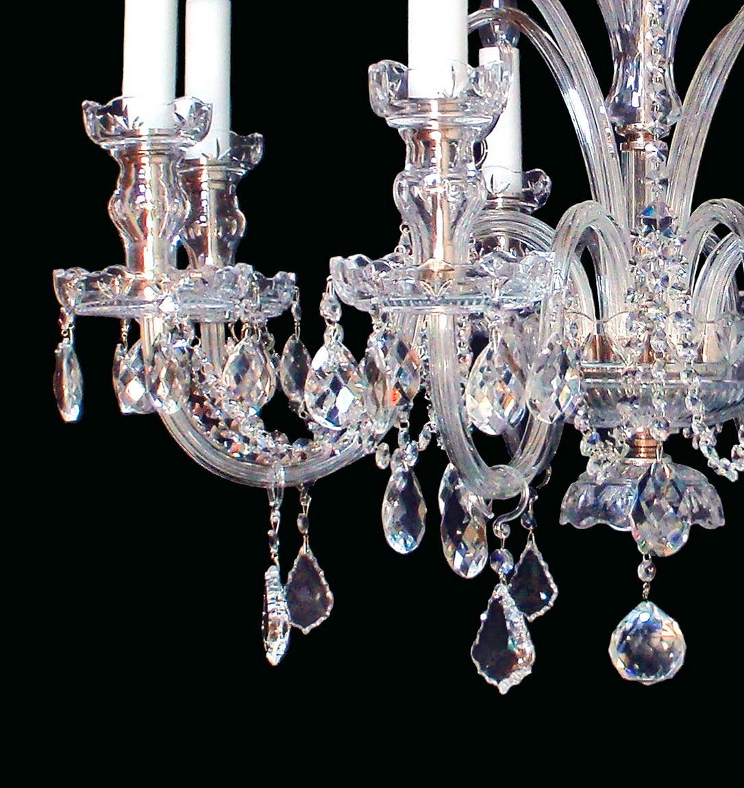 Détail des bras courbés en cristal et des pendentifs taillés suspendus aux anneaux.