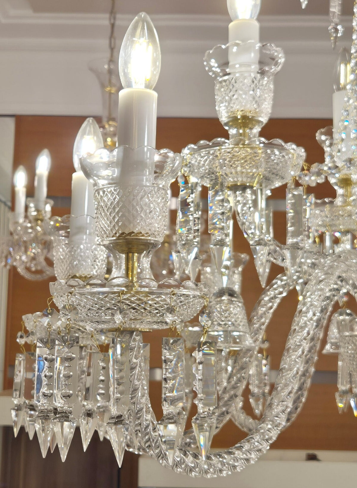 Gros plan sur les détails de cristal, bougies et pendeloques du luminaire.