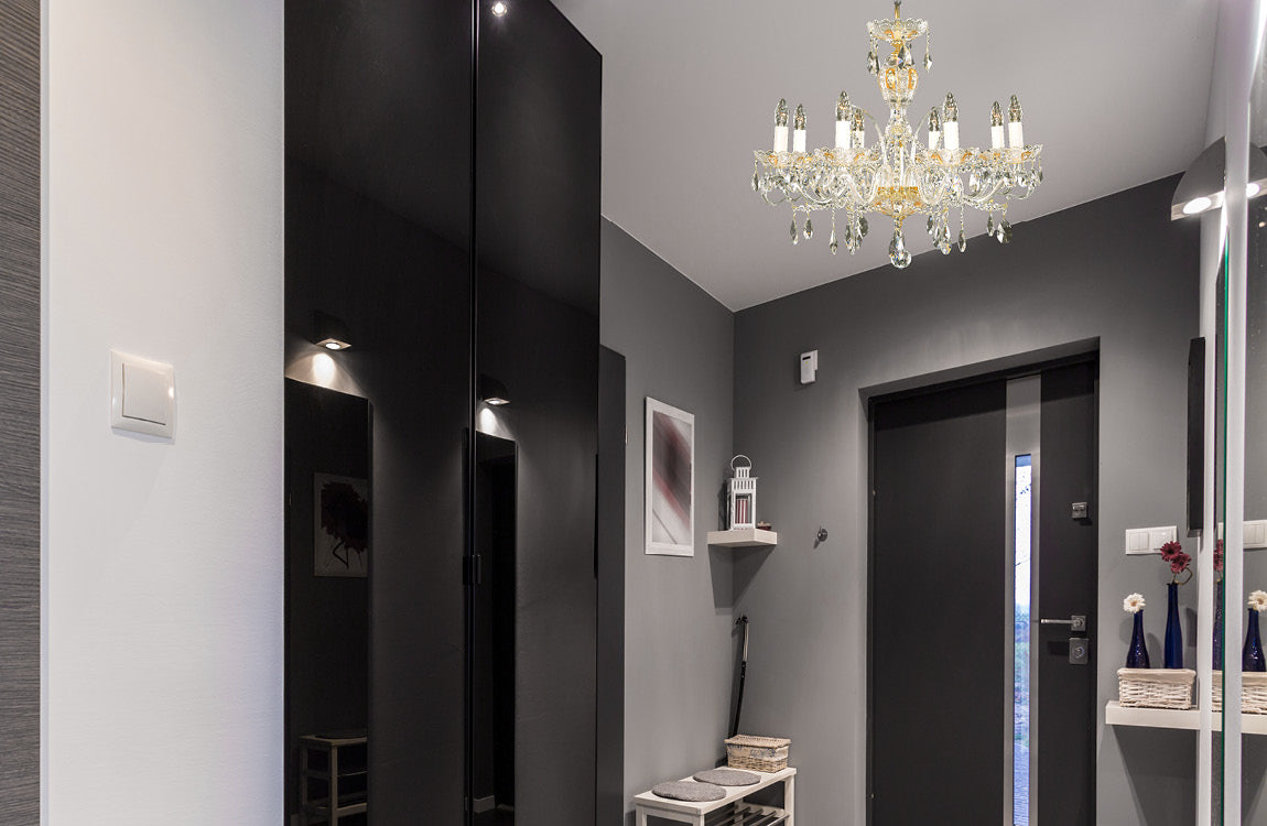 Lustre suspendu au plafond d'une entrée grise avec portes noires