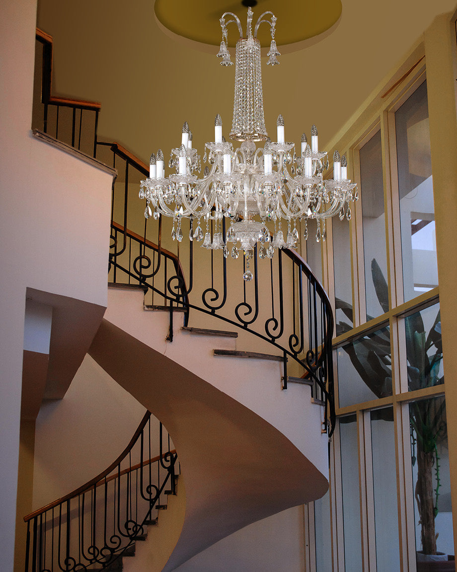 Lustre en cristal éclairé au-dessus d'un escalier courbe à rambarde en fer forgé.