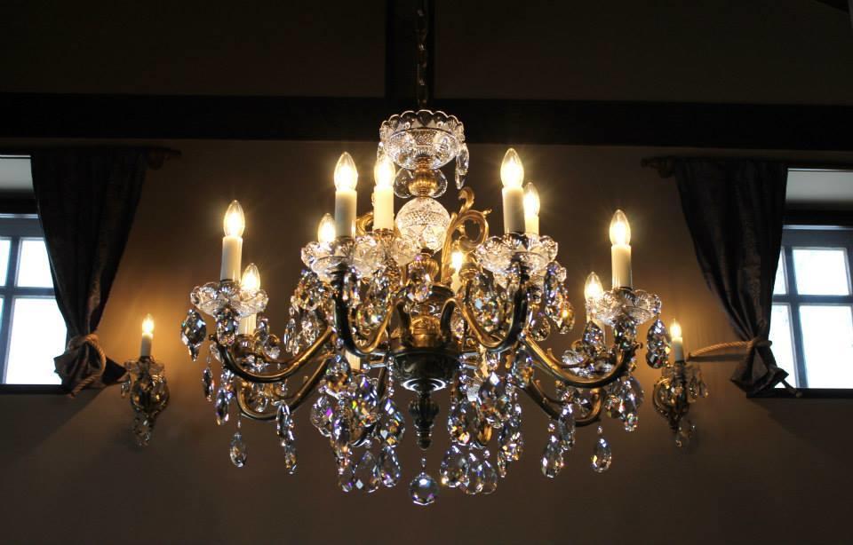 Lustre suspendu allumé dans un salon, tentures et fenêtres en arrière-plan