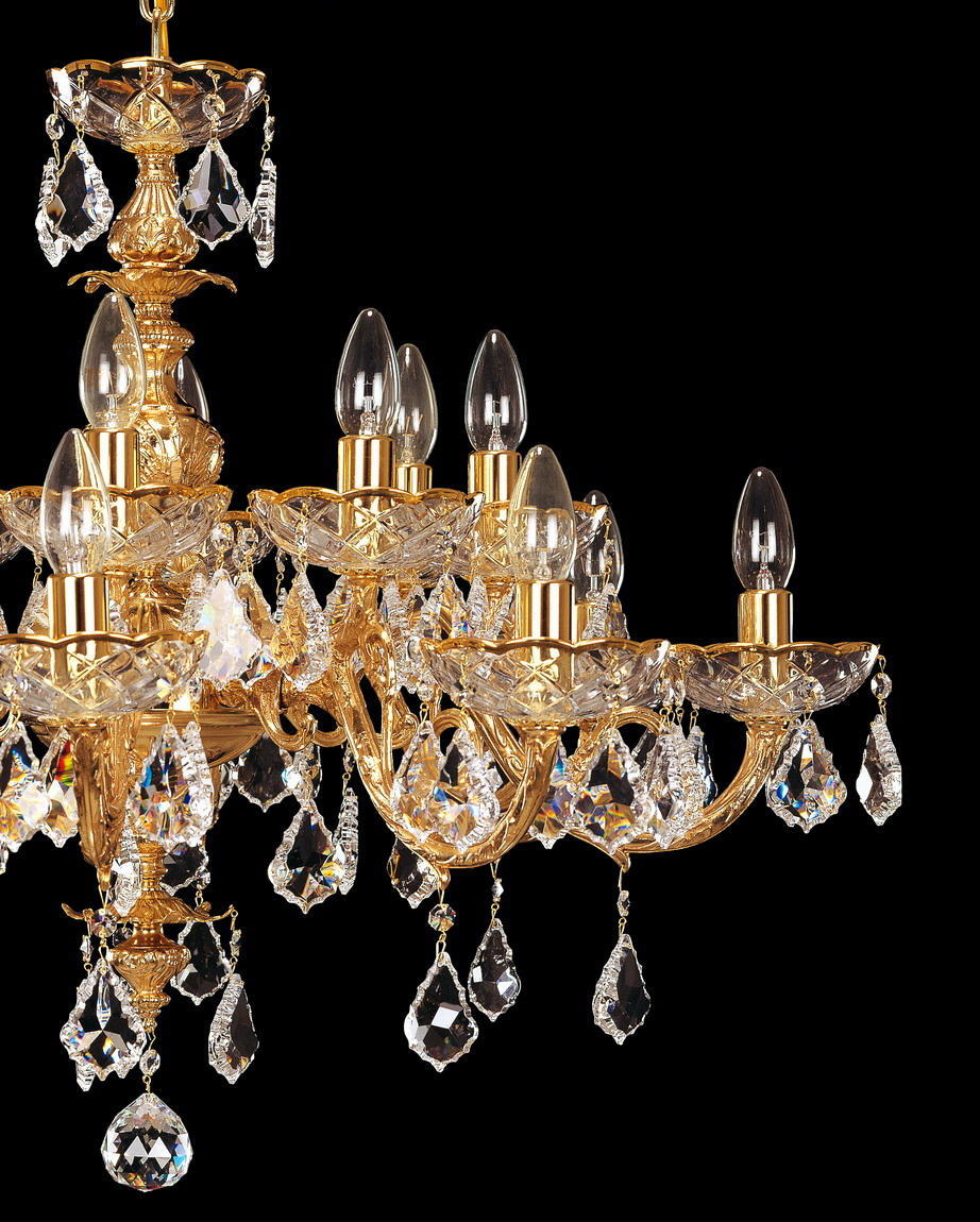 Gros plan sur les bras du lustre, coupelles ciselées, ampoules et pendeloques de cristal